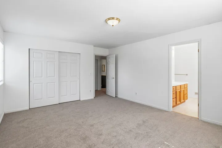 Recessed ceiling lighting, sliding panel closet doors, light-toned carpeting, and a built-in vanity with cabinetry