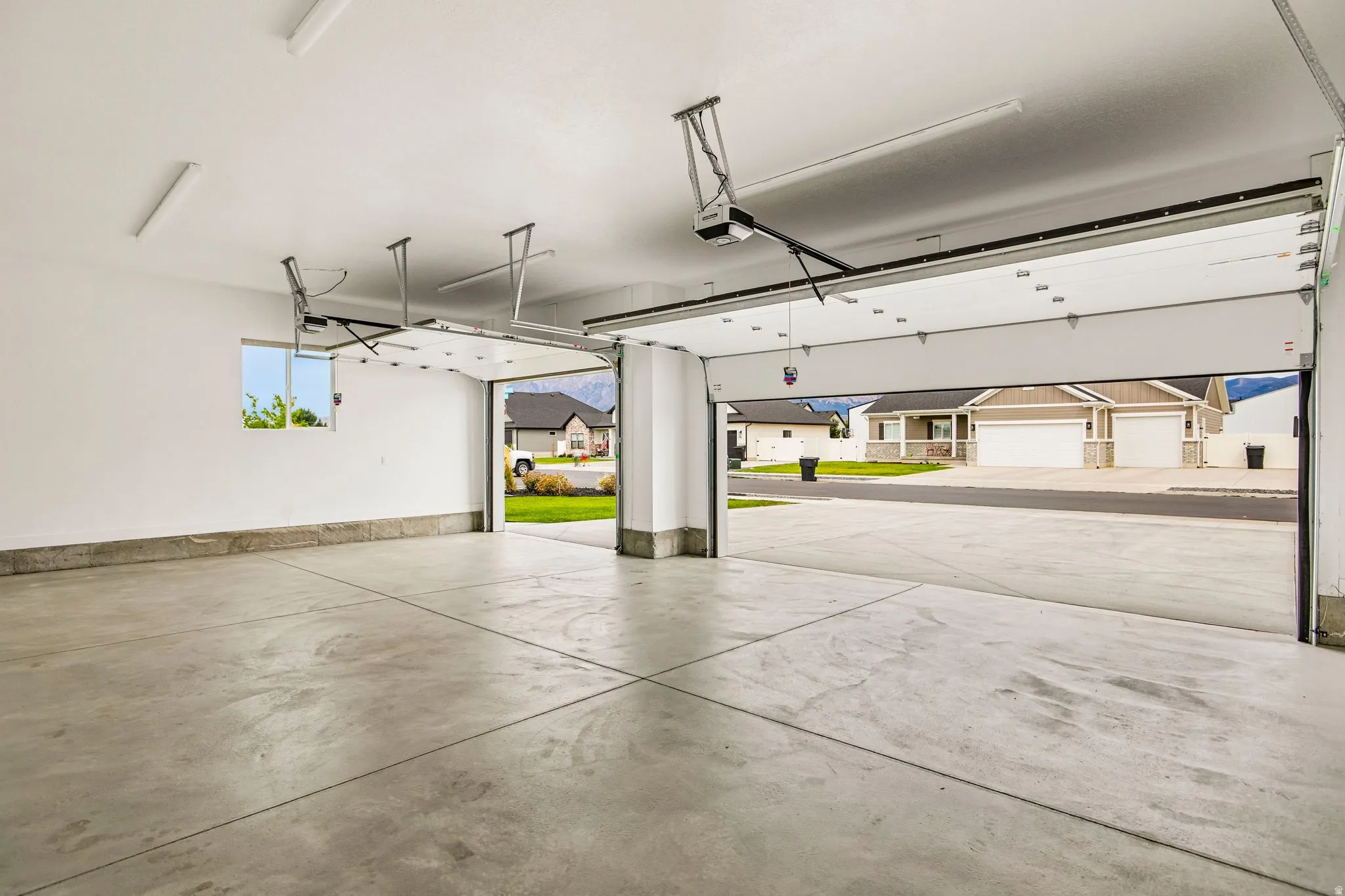 Expansive garage featuring a concrete floor, white walls, overhead lighting, and an automatic garage door opener