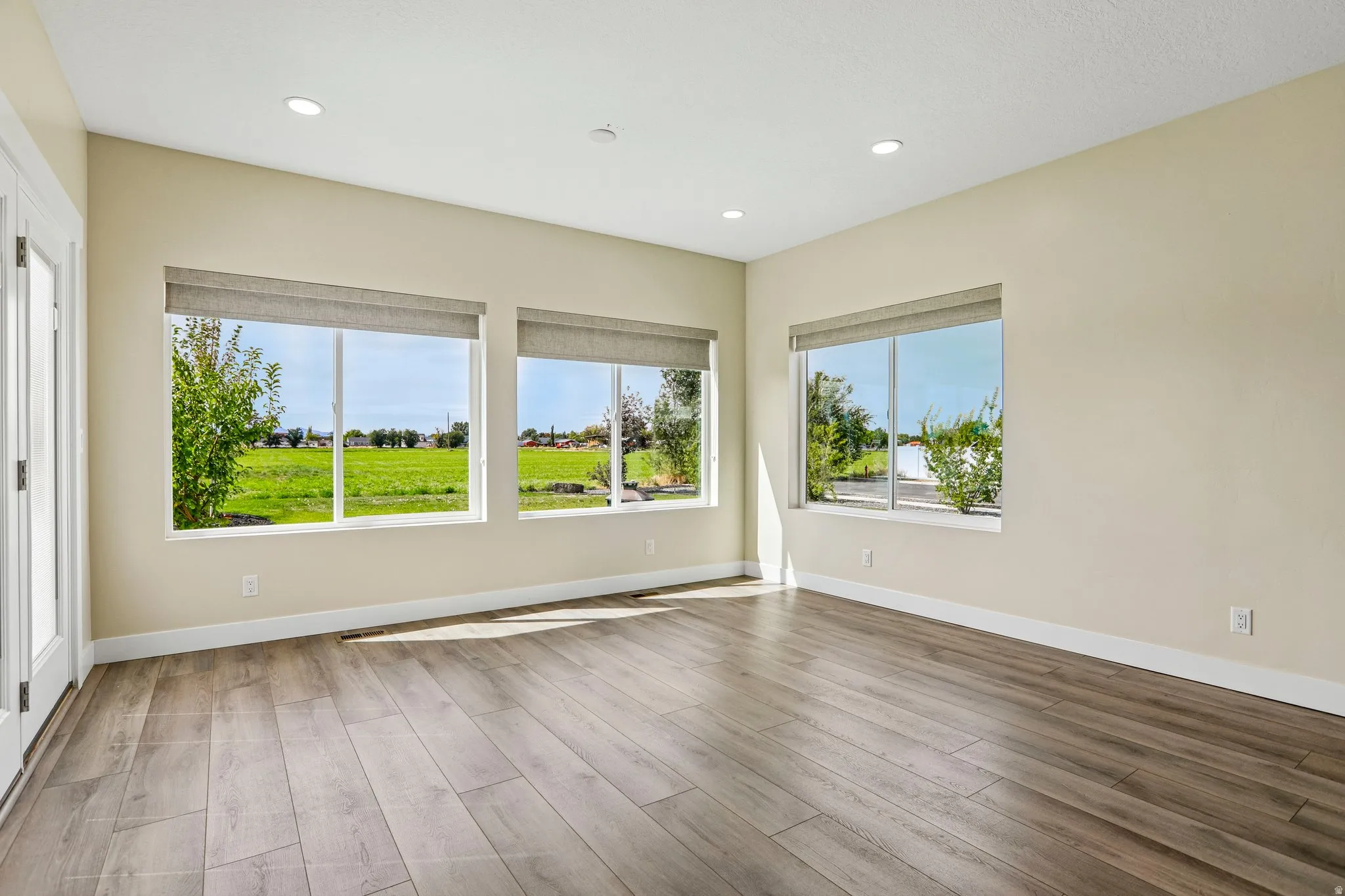 Wood-finish flooring, recessed lighting, multiple windows, French doors, and neutral wall tones