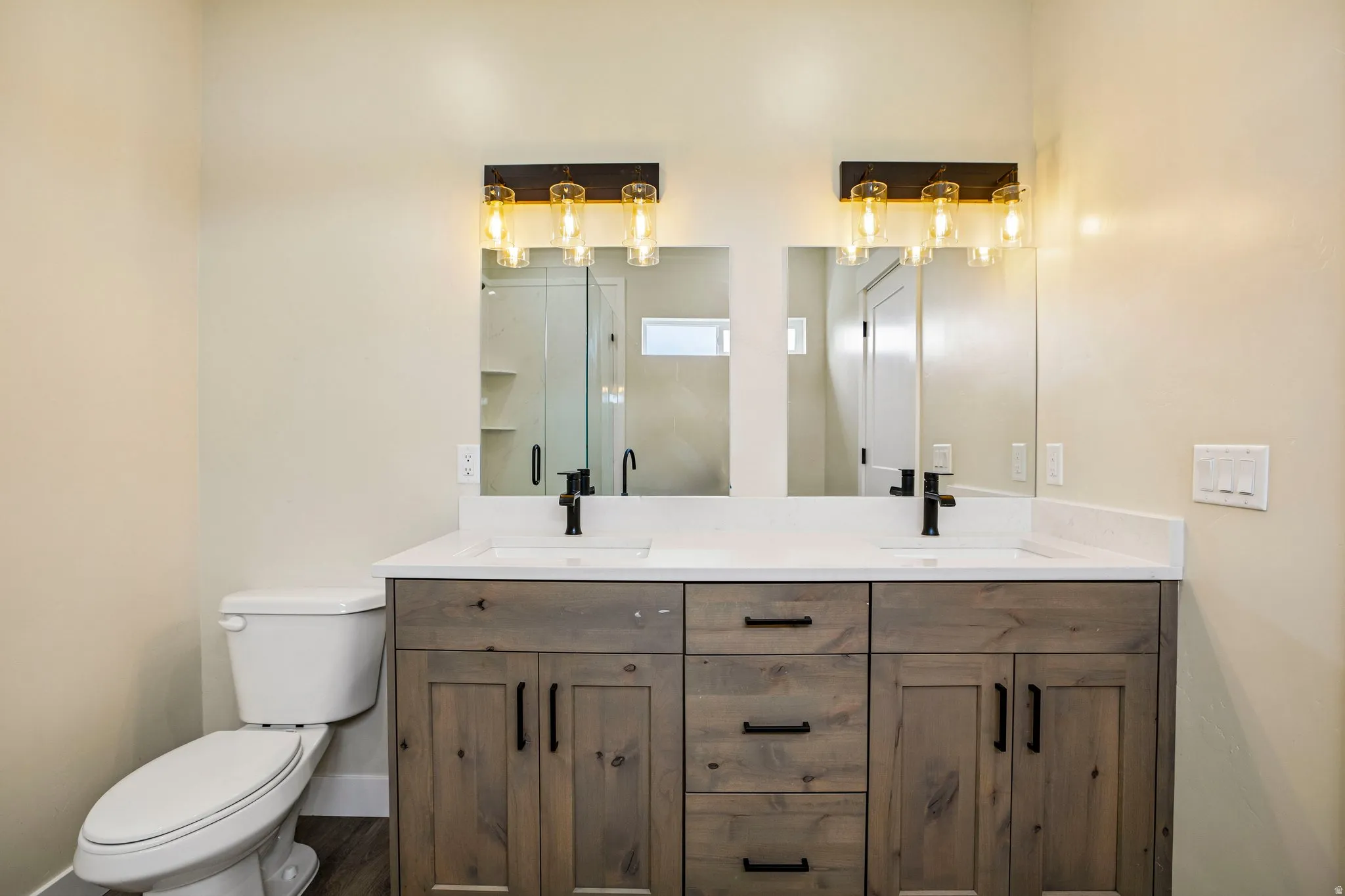 Dual vanity with wood-finish cabinetry, white countertop, and integrated sinks