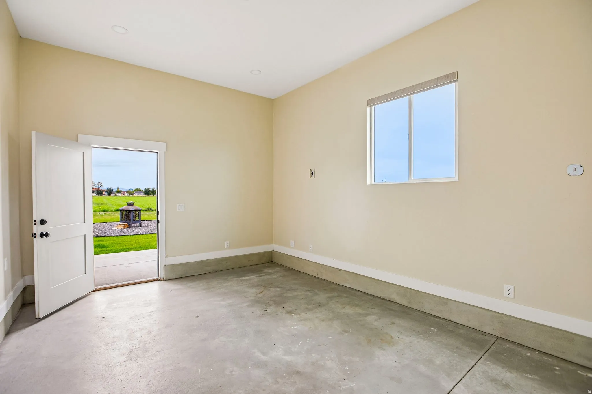 Concrete flooring, white trim, recessed lighting, and an exterior door leading to a patio