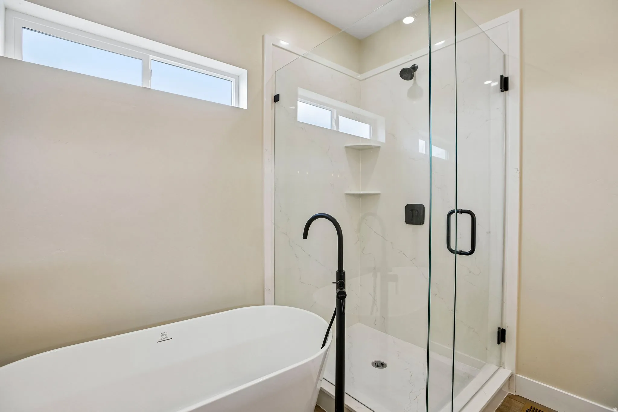 Freestanding soaking tub with matte black floor-mounted faucet