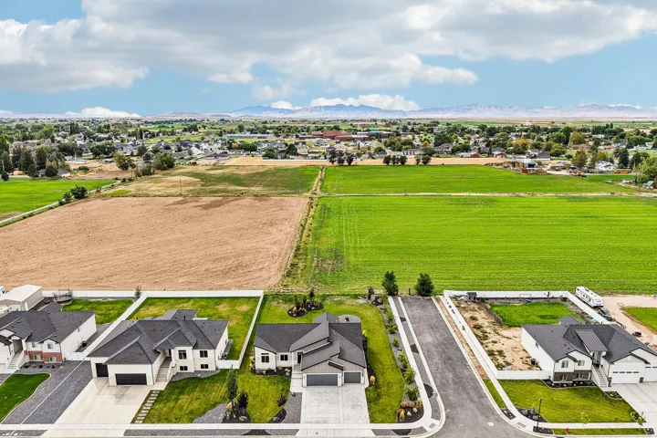 Modern residential development with a mountain backdrop, surrounded by expansive agricultural fields