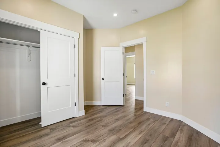 Wood-finish flooring, recessed lighting, neutral wall tones, white trim, and a white interior door