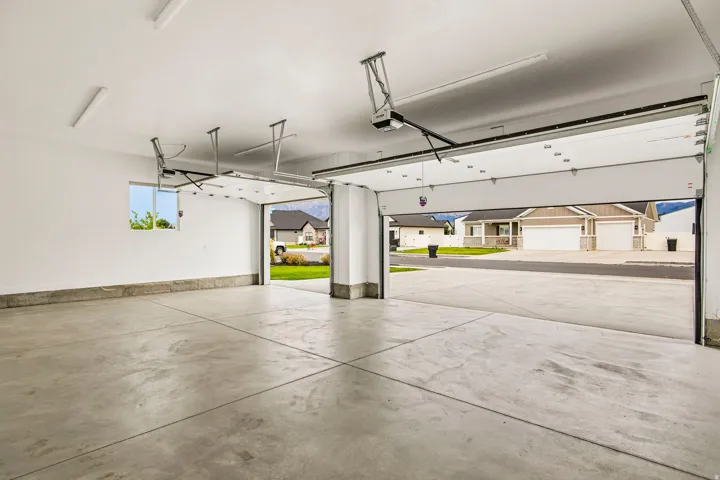 Expansive garage featuring a concrete floor, white walls, overhead lighting, and an automatic garage door opener