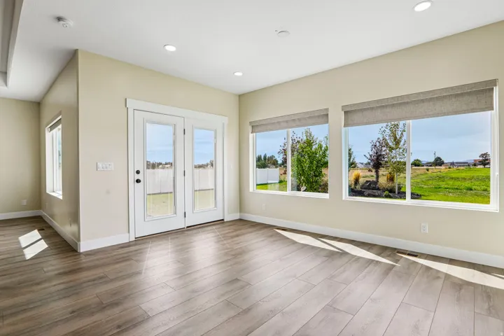 Wood-finish plank flooring, recessed ceiling lighting, dual pane windows with roller shades, and white frame French doors