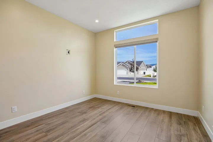 Recessed ceiling lighting, a large picture window, an upper transom window, wood-finish flooring, and white trim