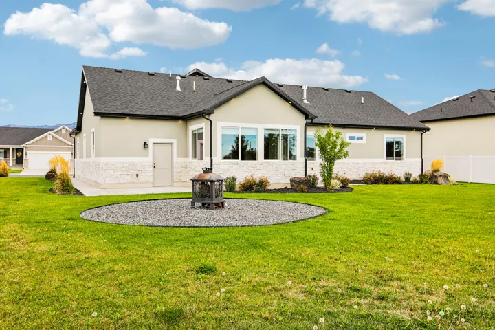 Expansive green space featuring a concrete patio, decorative gravel area, and stone accents