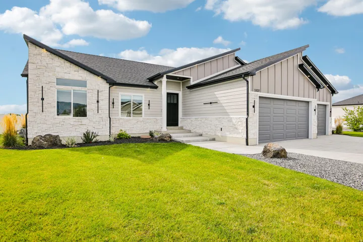 Modern exterior with a stone and siding facade, multi-pitch roofline, attached multi-car garage, and concrete driveway