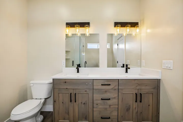 Dual vanity with wood-finish cabinetry, white countertop, and integrated sinks