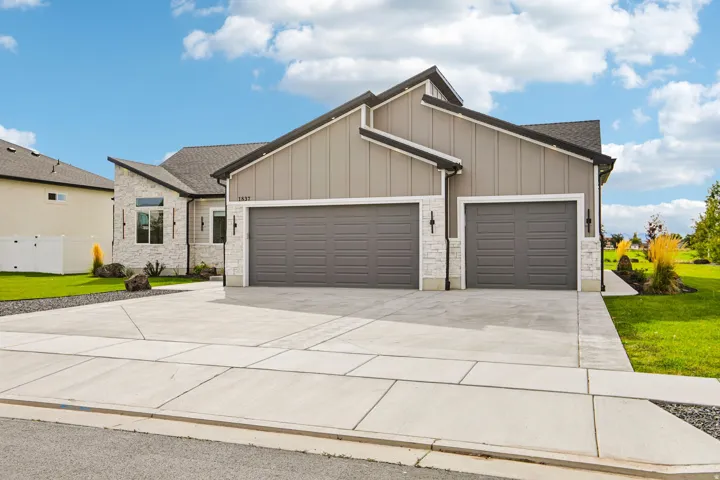 Contemporary home exterior featuring stone and vertical panel siding, an attached two-car garage, and a concrete driveway
