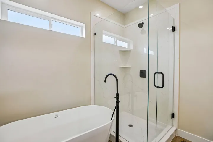 Freestanding soaking tub with matte black floor-mounted faucet