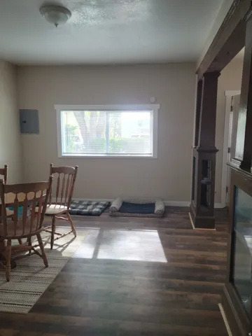 Wood-finish flooring throughout, complemented by a prominent window, a ceiling-mounted light fixture, and a decorative structural column