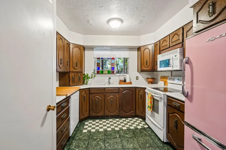 Kitchen featuring wood cabinetry, a white electric range, a built-in microwave, and a stainless steel sink