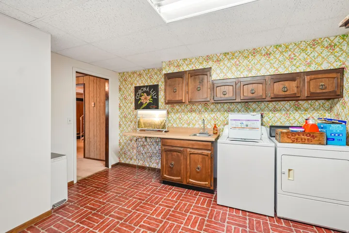 Brick-patterned flooring, built-in cabinetry, and a utility sink
