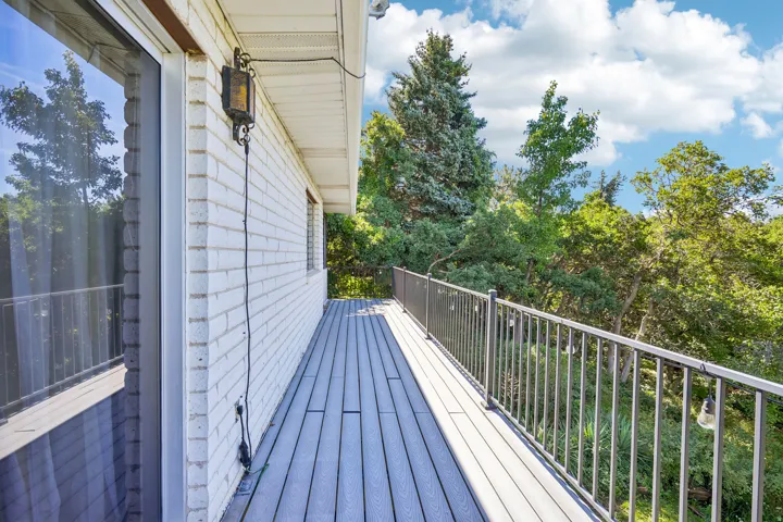 Expansive outdoor deck featuring composite decking, metal railings, and a brick exterior