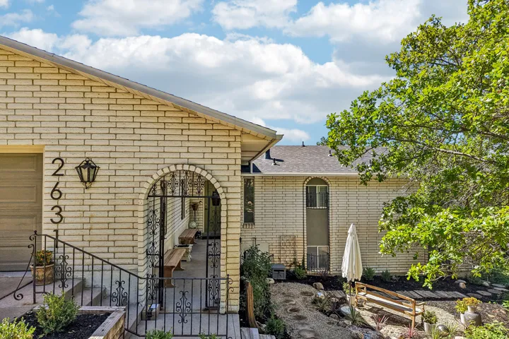 Brick exterior with an arched entry, wrought iron gate, and garage door