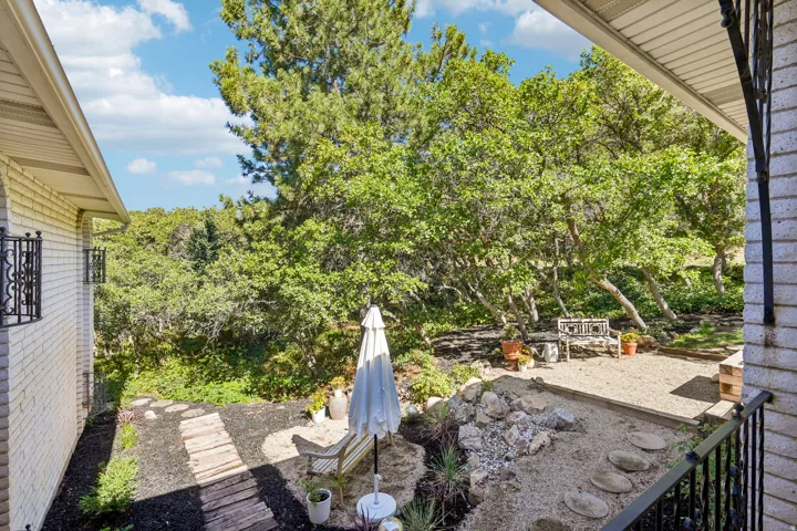 Outdoor patio featuring gravel and stone landscaping with a wood-finish pathway, surrounded by mature trees