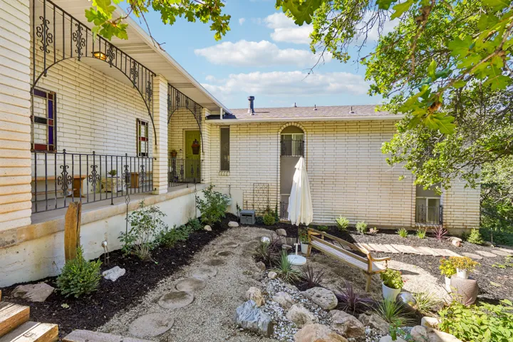 White brick exterior featuring a covered porch with wrought iron railing