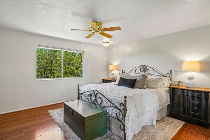 Hardwood-style flooring, a window offering exterior views, and a ceiling fan with integrated lighting