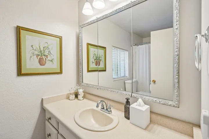 Vanity with an integrated sink, polished chrome faucet, and a large mirrored medicine cabinet with decorative framing