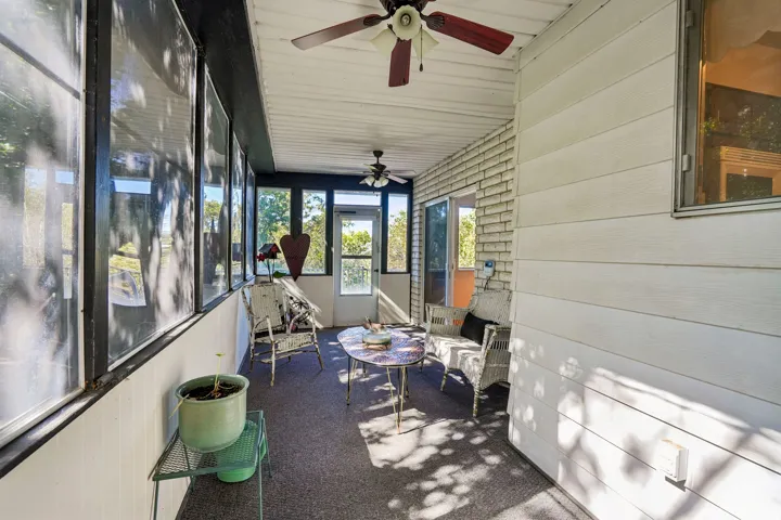 Enclosed porch with multiple windows, two ceiling fans, and a carpeted floor