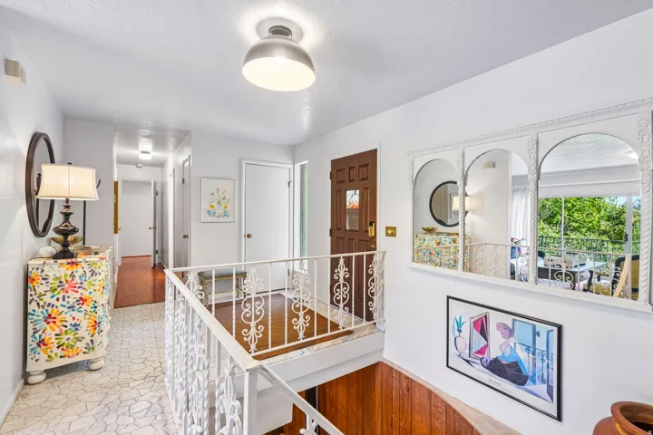 White decorative railing, recessed lighting, wood-finish flooring, white paneled doors, and arched decorative mirrors