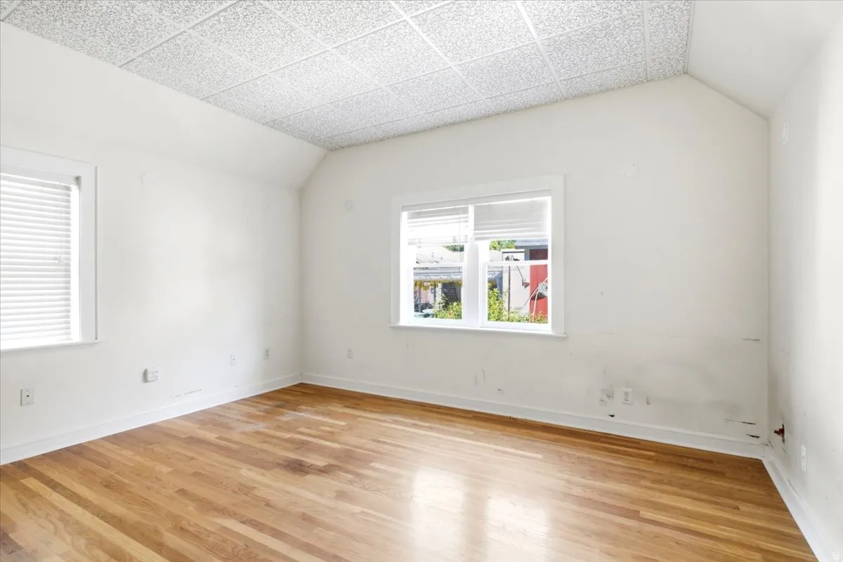 Wood-finish flooring with white trim, vaulted ceiling, and two windows