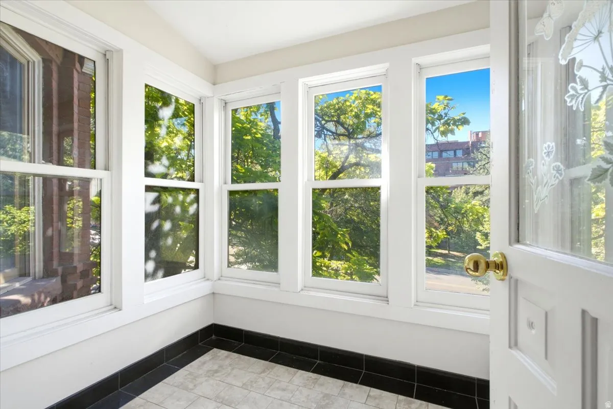 sun porch Multiple windows, white trim, black tile baseboard, patterned floor tiles, white door with decorative glass