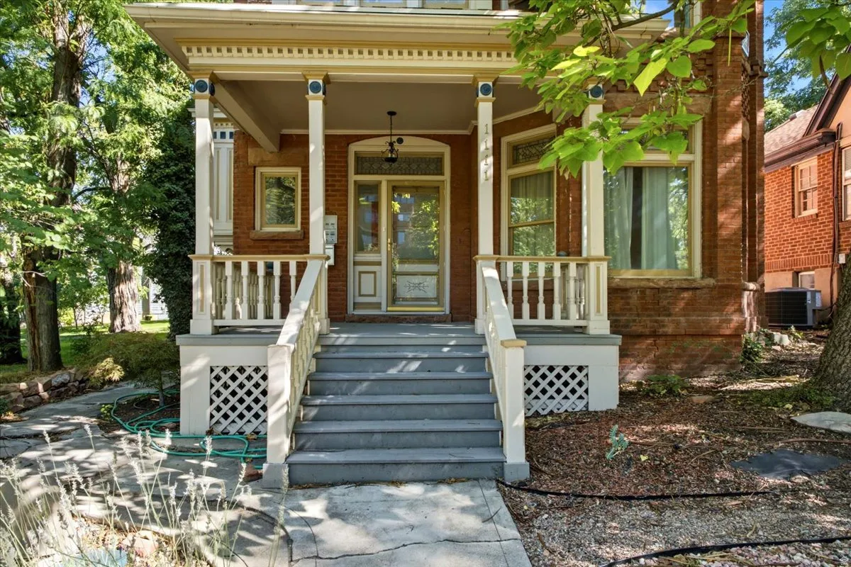 Brick exterior with decorative trim, covered porch, porch railings, and detailed entry door