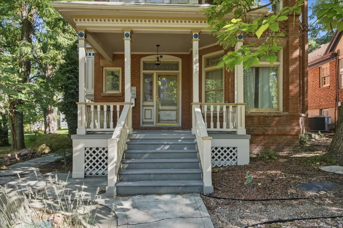 Brick exterior with a covered porch, white balustrade, detailed trim, and a prominent front entry