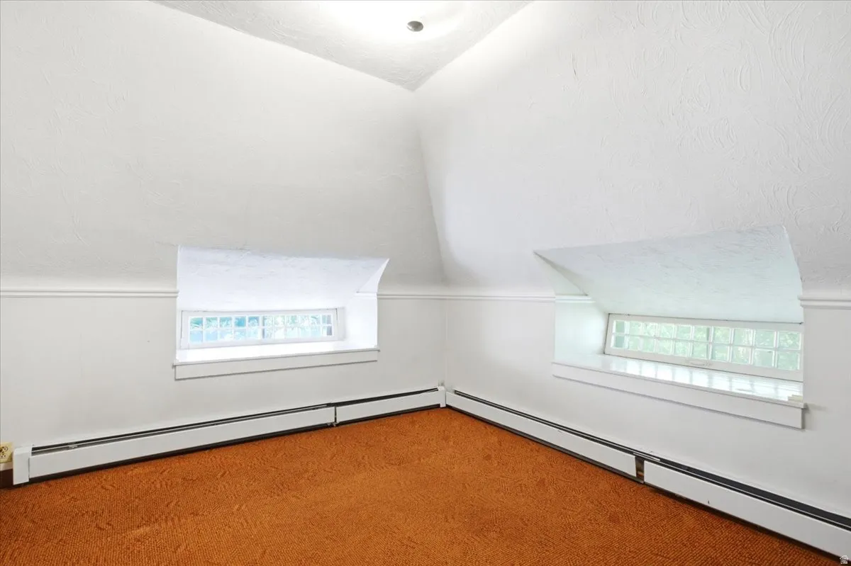 Angled walls with white textured finish, two recessed windows, and baseboard heating units