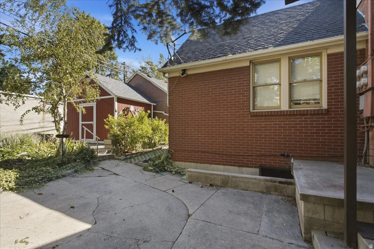Red brick exterior with a dark shingle roof and a detached red shed