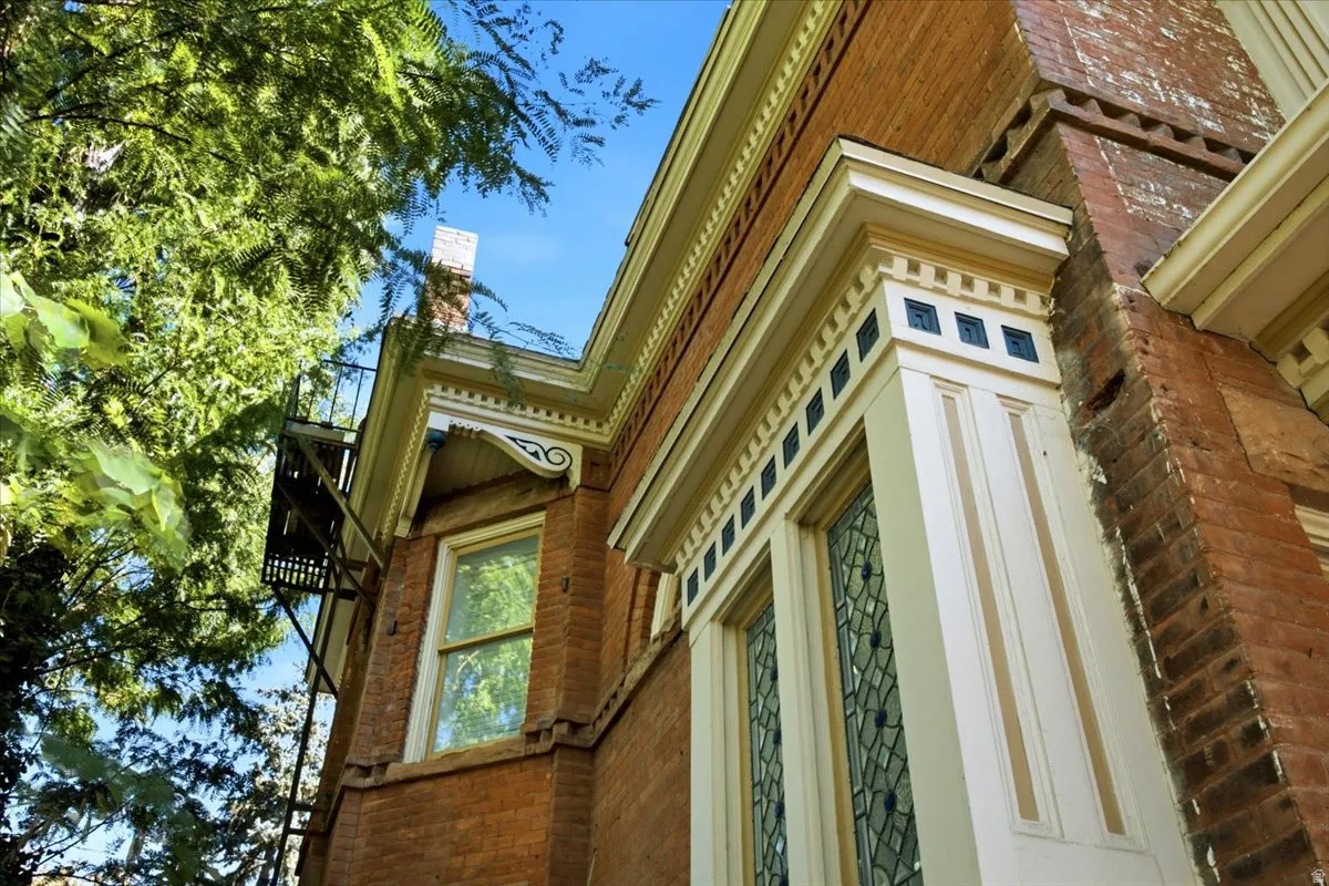 Brick exterior with ornate white trim, leaded glass window, and decorative corbels
