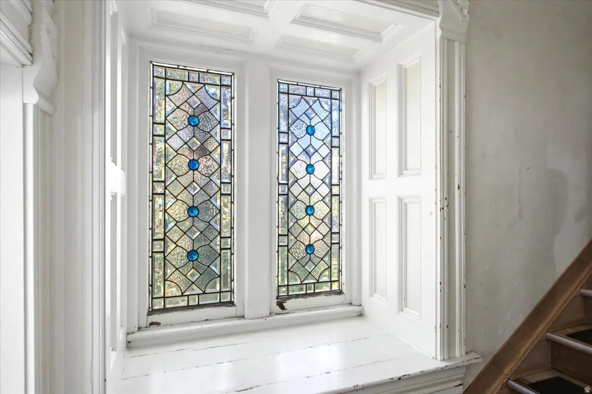 Stained glass windows with blue accents, coffered ceiling, paneled window surrounds, and a wooden handrail