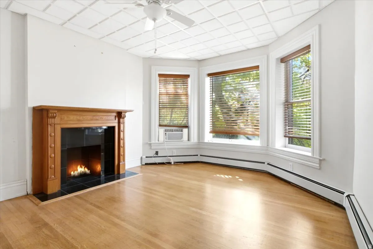 Second apartment Hardwood flooring, decorative ceiling, bay windows, wood-finish mantel with tile surround, and an overhead ceiling fan