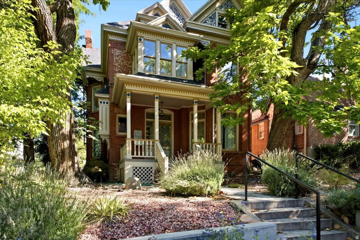 Brick exterior, detailed trim work, covered front porch, stone steps with handrails, established landscaping