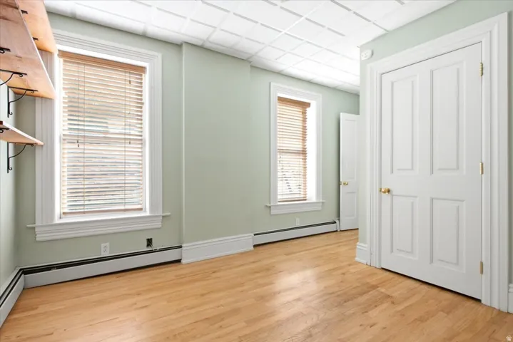 Wood-finish flooring, white window trim, white baseboard trim, and a white paneled ceiling