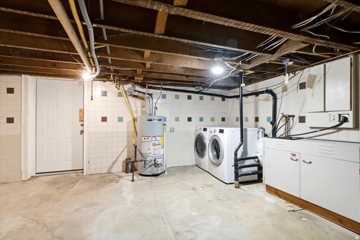 Laundry area with white tile walls featuring accent squares