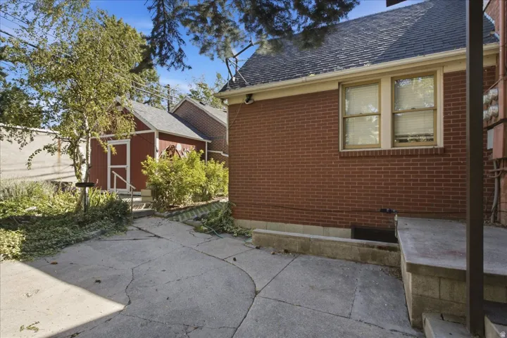 Red brick exterior with a dark shingle roof and a detached red shed