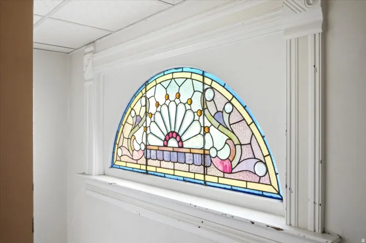 Arched stained-glass window with vibrant color palette and decorative millwork trim