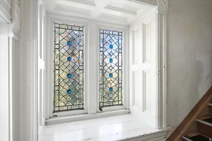 Stained glass windows with blue accents, coffered ceiling, paneled window surrounds, and a wooden handrail