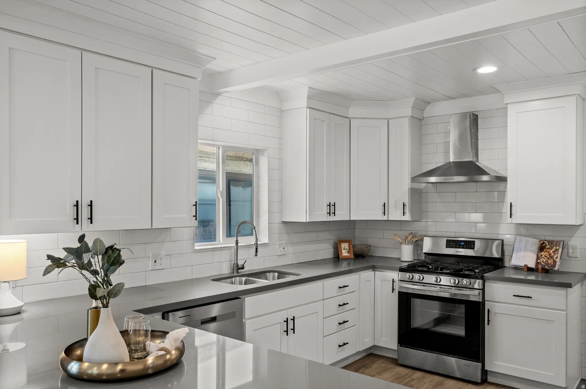 Kitchen featuring white shaker cabinetry, stainless steel appliances, a subway tile backsplash, gray countertops, and wood-finish flooring