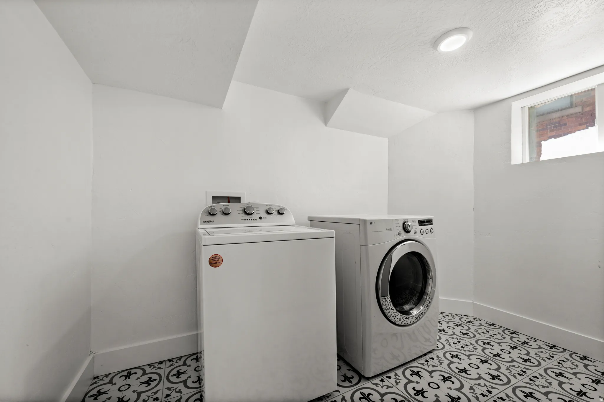 Laundry area featuring patterned tile flooring, a recessed ceiling light, and a window