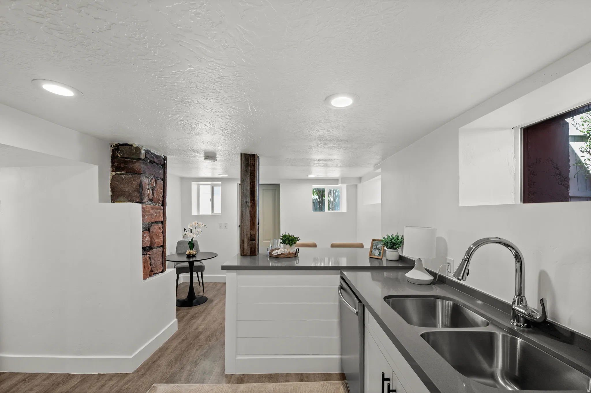 Galley kitchen with dual basin stainless steel sink, solid surface countertops, and wood-finish flooring