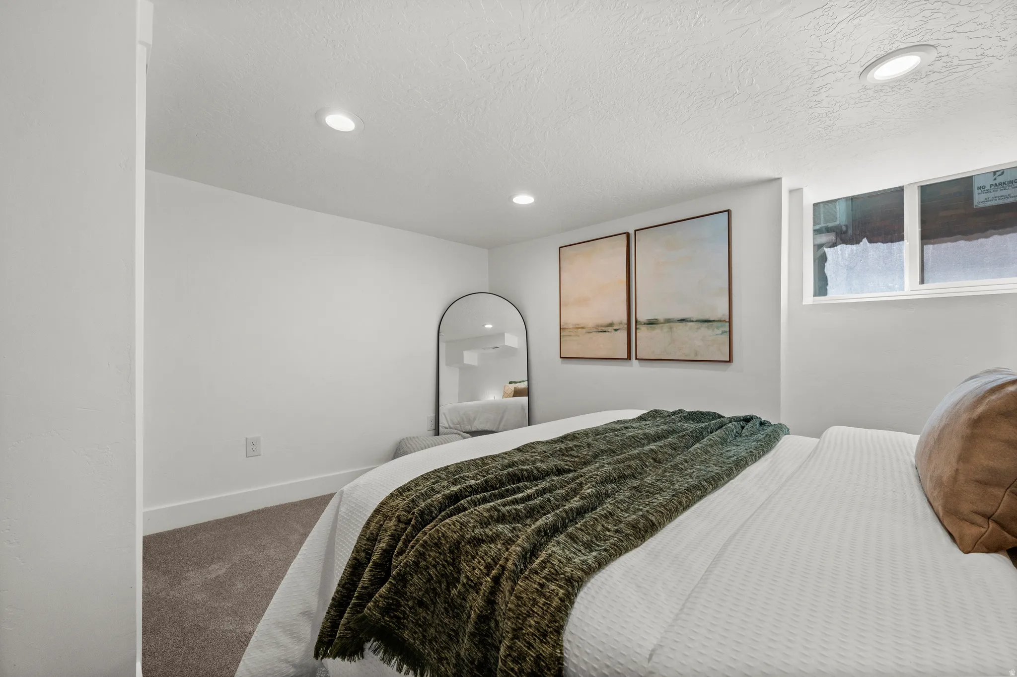 Recessed ceiling lighting, white walls, carpet flooring, and a single window