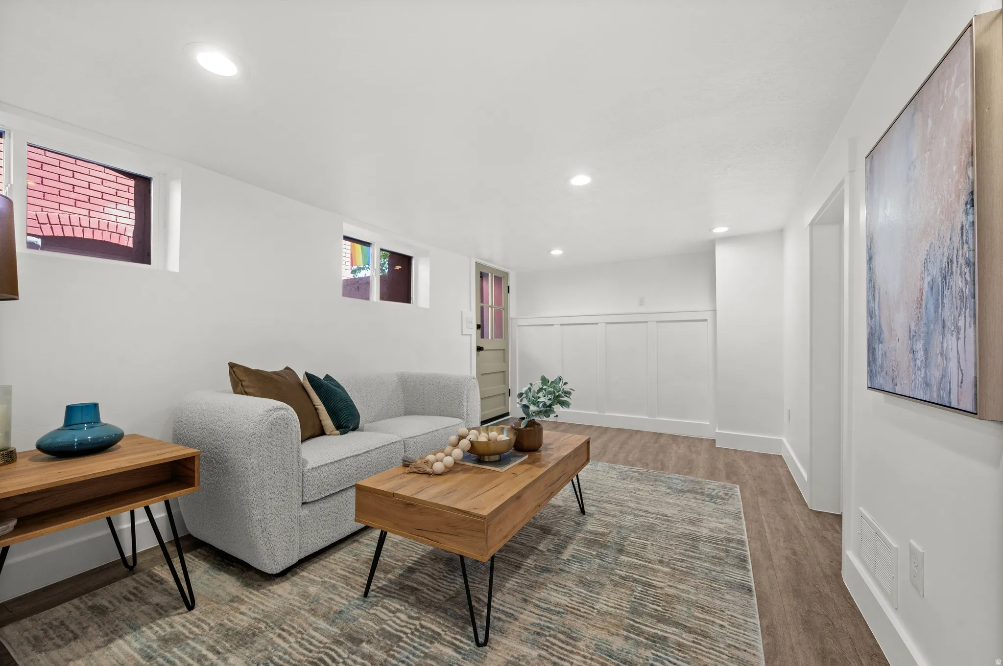 Recessed lighting, wood-finish flooring, white board and batten wall detailing, and a solid panel door