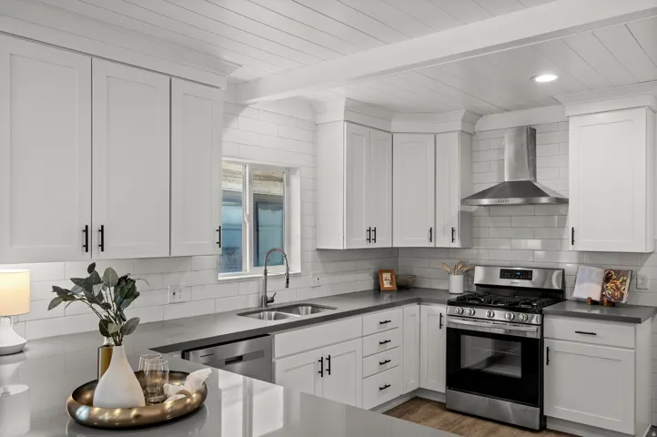 Kitchen featuring white shaker cabinetry, stainless steel appliances, a subway tile backsplash, gray countertops, and wood-finish flooring