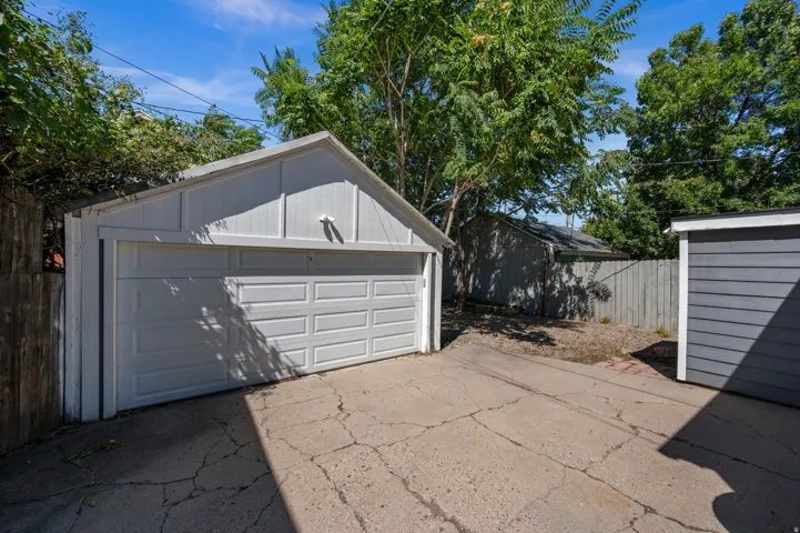 Detached single-car garage featuring a white paneled garage door and a concrete driveway