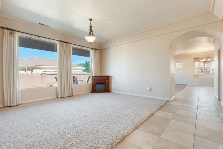 Carpeted living area featuring a decorative corner fireplace, large windows, and a chandelier